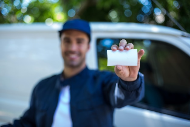 Smiling delivery man showing business card 