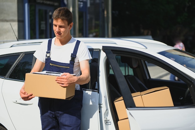 Smiling delivery man standing in front of his car