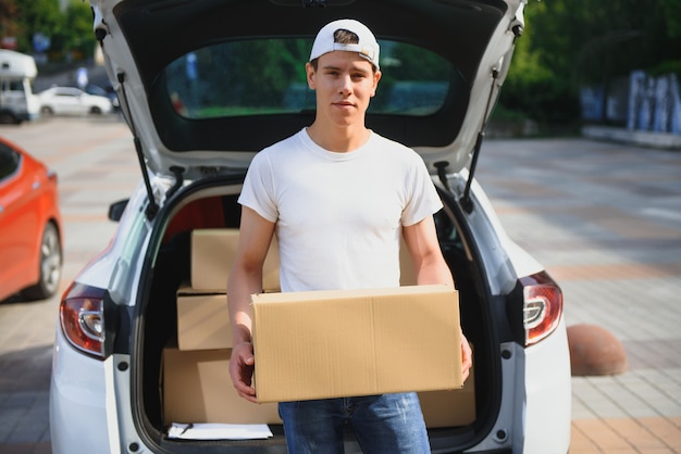 Smiling delivery man standing in front of his car