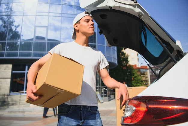 Smiling delivery man standing in front of his car