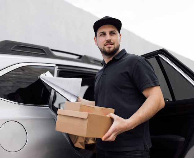 Smiling delivery man standing in front of his vehicle