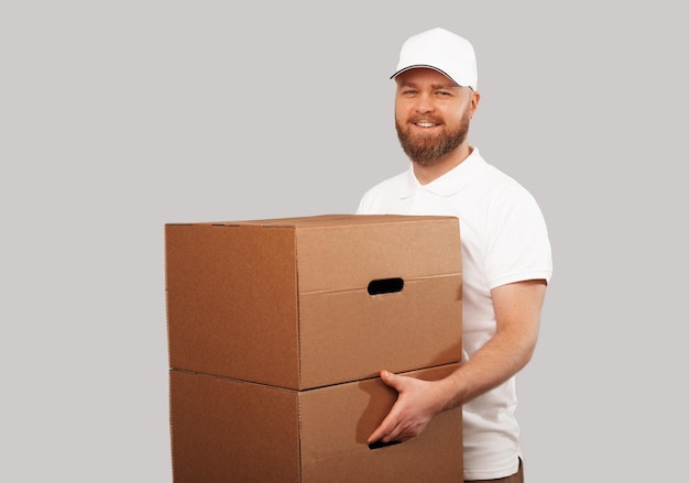 Smiling delivery man wearing white uniform hold some big moving boxes