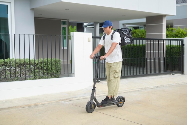 Smiling delivery man with thermal backpack riding on an electric scooter deliver online concept