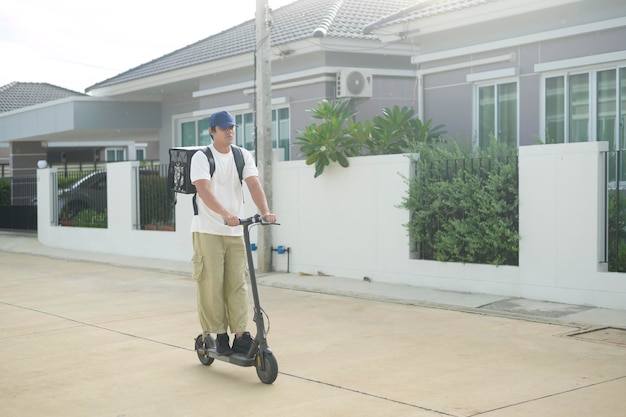 Smiling delivery man with thermal backpack riding on an electric scooter deliver online concept