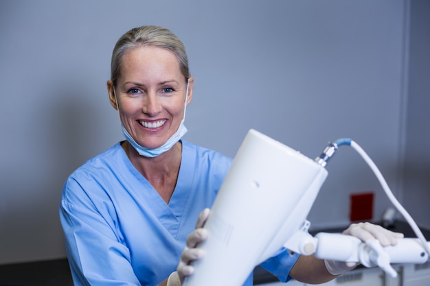 Smiling dental assistant adjusting light in clinic