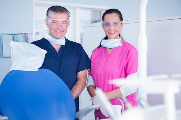 Smiling dentist and assistant with protective glasses