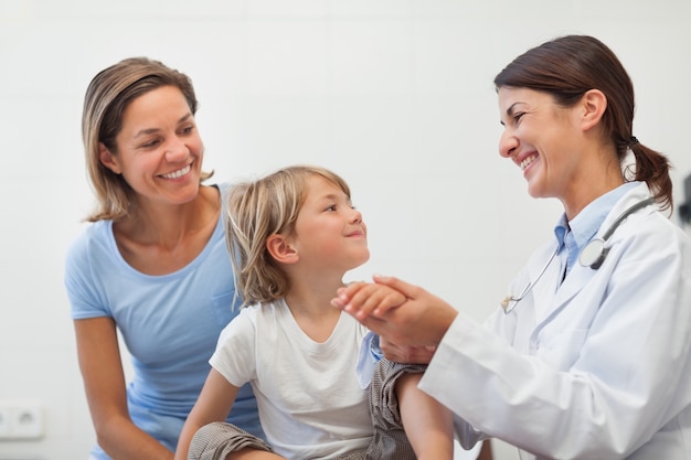 smiling doctor auscultating the forearm of a child