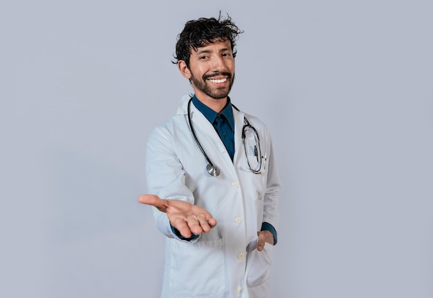 Smiling doctor extending hand in welcome Young doctor extending hand to camera Smiling doctor extending hand isolated