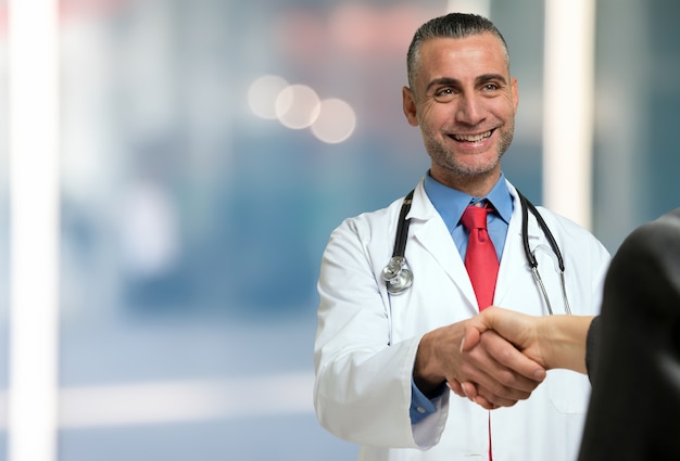 Smiling doctor giving an handshake to a patient