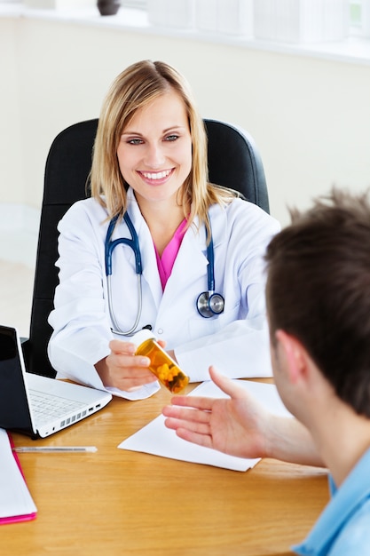 Smiling doctor givng pills to her patient 