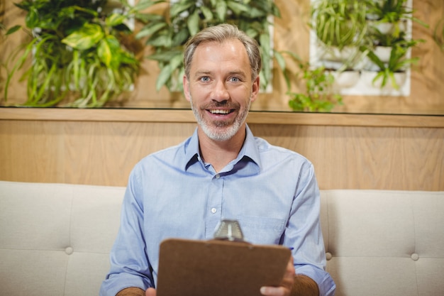 Photo smiling doctor holding clipboard in clinic