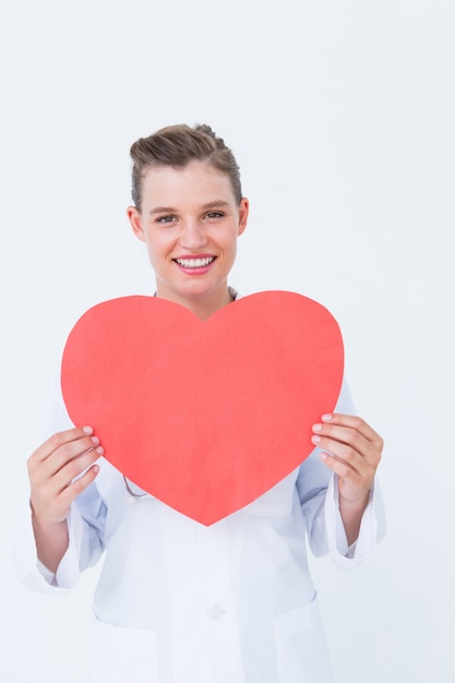 Smiling doctor holding heart card 