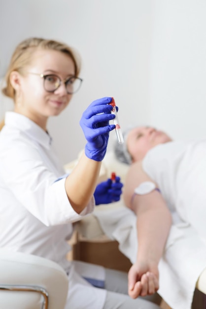 Medico sorridente in guanti di lattice che tengono la provetta esame del sangue dalla vena della mano2