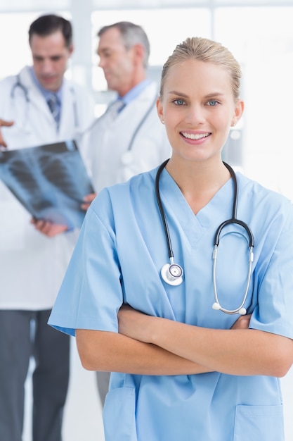 Smiling doctor looking at camera while her colleagues works 