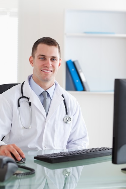 Smiling doctor sitting on his computer