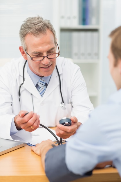 Smiling doctor taking his patients blood pressure