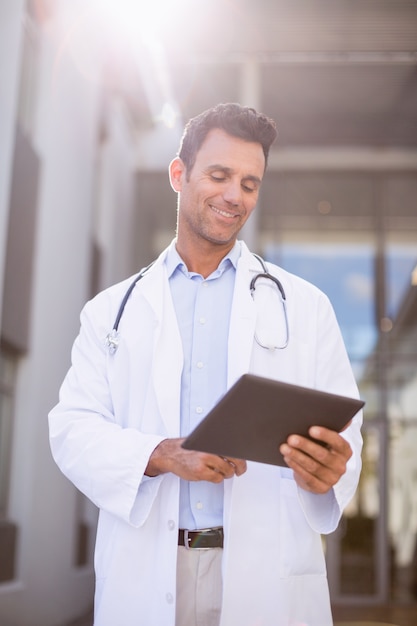 Smiling doctor using digital tablet