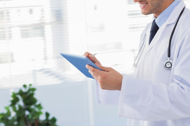 Smiling doctor using his tablet pc