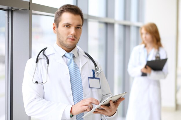 Foto medico sorridente che aspetta la sua squadra stando in piedi