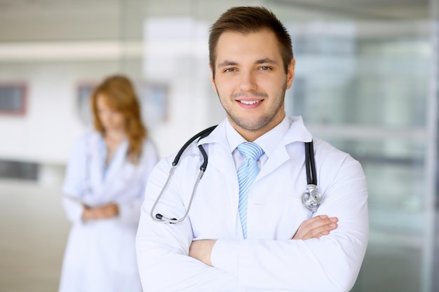 Smiling doctor waiting for his team while standing upright