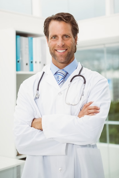 Smiling doctor with arms crossed in medical office