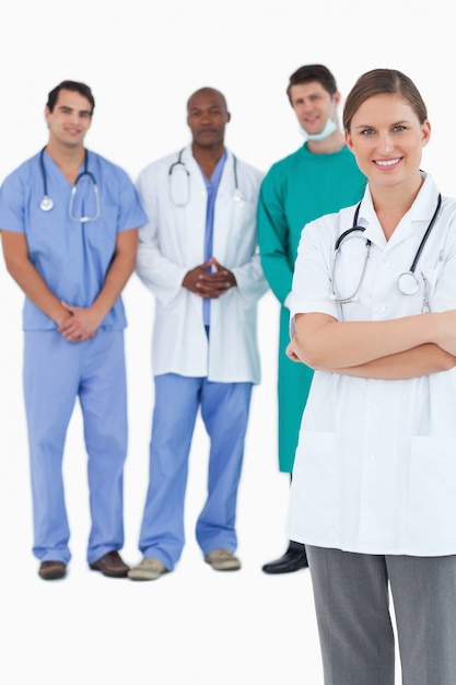 Photo smiling doctor with folded arms and colleagues behind her