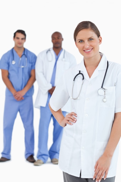 Smiling doctor with male colleagues behind her