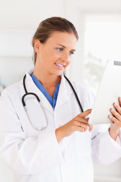 Smiling doctor with a stethoscope pointing at a file