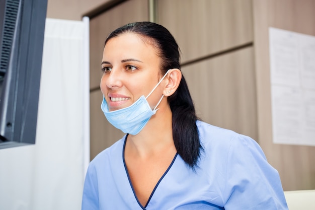 Smiling doctor woman in blue medical uniform and mask