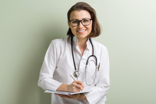 Smiling doctor woman with stethoscope taking notes