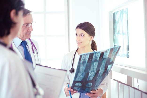 Улыбающиеся врачи обсуждают диагноз пациента, глядя на рентген в больнице