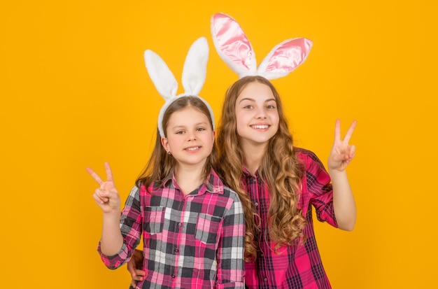 Smiling easter children in bunny ears on yellow background peace