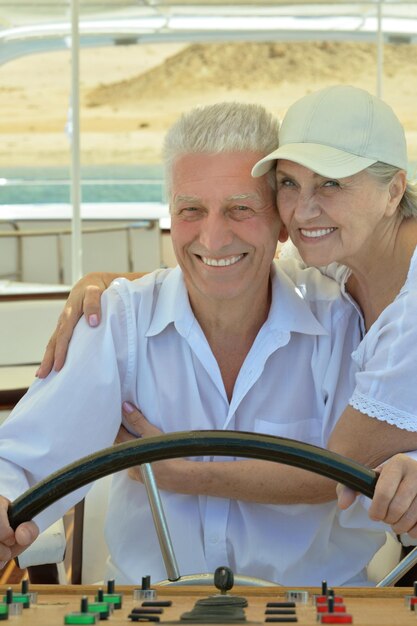 Smiling elderly couple resting on yacht in sea