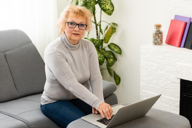 Smiling elderly senior woman with laptop at home.