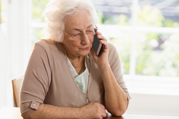 Smiling elderly woman phone calling at home