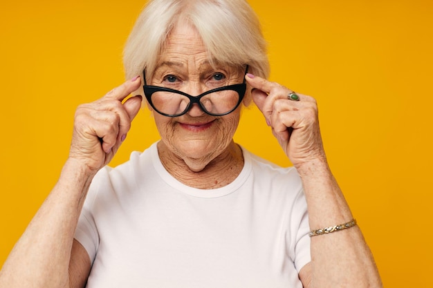 Smiling elderly woman vision problems with glasses yellow background