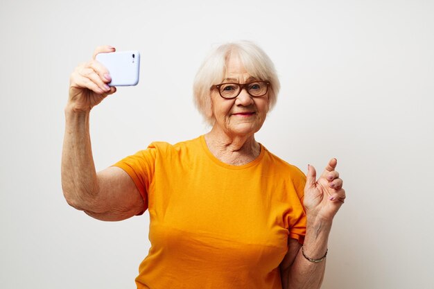 Smiling elderly woman in a yellow tshirt posing communication by phone closeup emotions