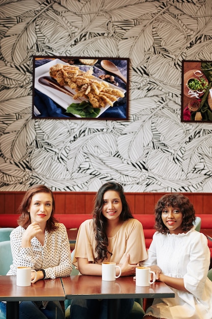 Smiling elegant women in trendy coffeeshop