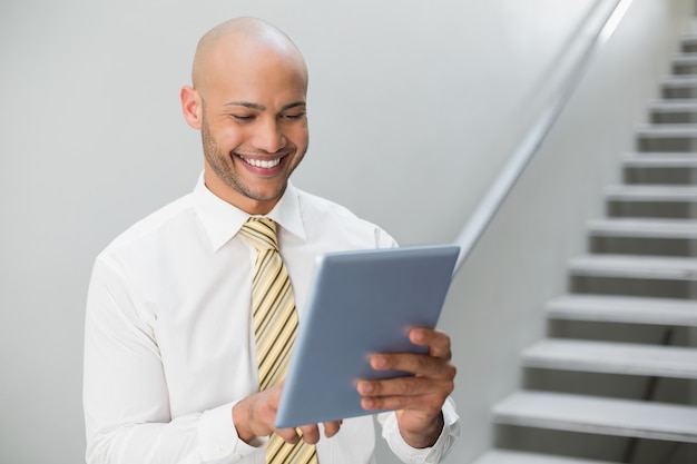 Smiling elegant young businessman using digital tablet