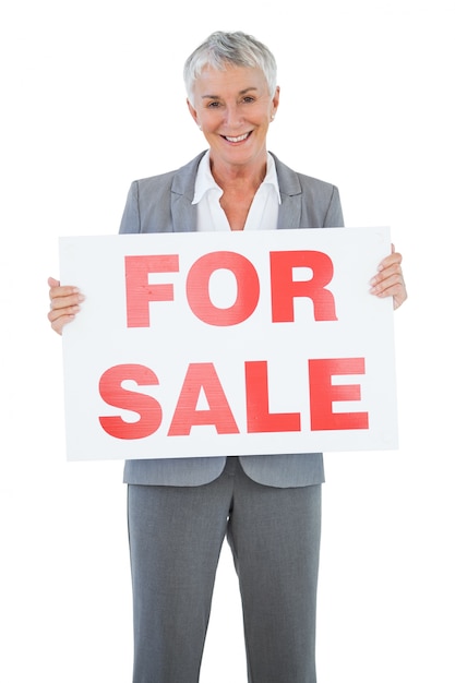 Smiling estate agent holding for sale sign