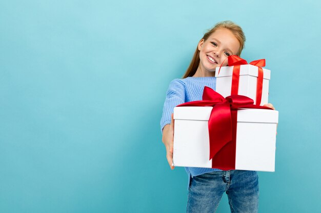 Smiling european girl holding a gift on a light blue  with copyspace