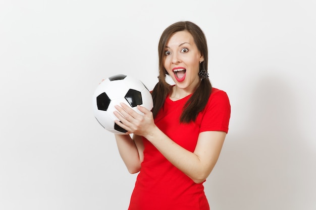 Smiling european young woman, two fun pony tails, football fan\
or player in red uniform holding classic soccer ball isolated on\
white background. sport play football health, healthy lifestyle\
concept.