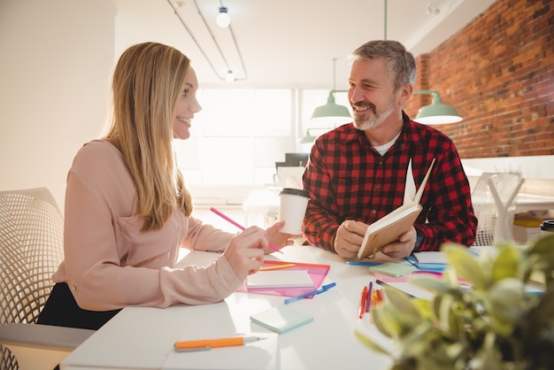 Smiling executives discussing over diary