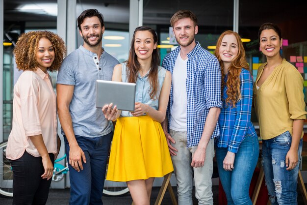 Foto quadri sorridenti che discutono sopra la compressa digitale nell'ufficio