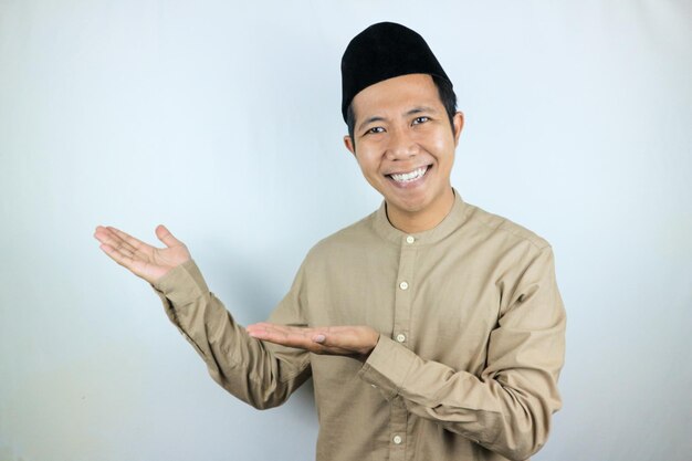 Foto espressione sorridente di un uomo musulmano asiatico che presenta e mostra uno spazio vuoto concetto pubblicitario