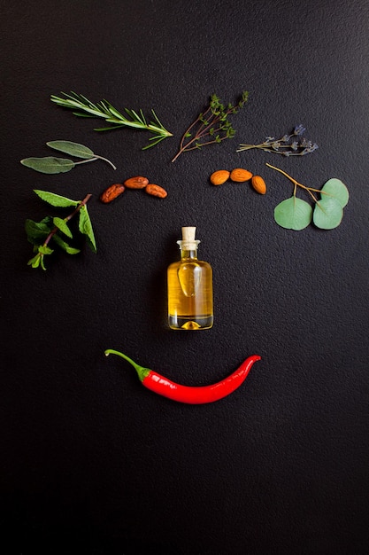 Smiling face making from herbs and bottle of essential oil on black background top view flat lay Healthy organic handmade cosmetics