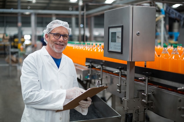 Smiling factory engineer maintaining record on clipboard in factory