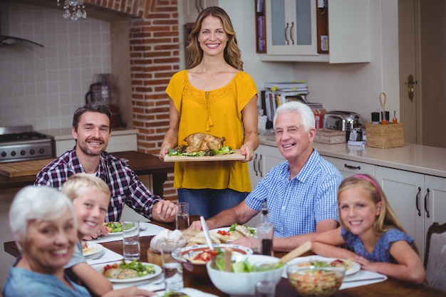 Smiling family at dining table with mother standing