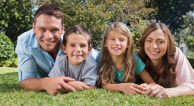 Foto famiglia sorridente che si trova sull'erba