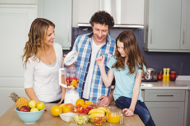 Smiling family preparing fruit juice 